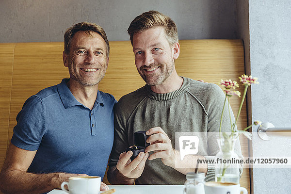 Portrait eines schwulen Paares mit Ehering im Café