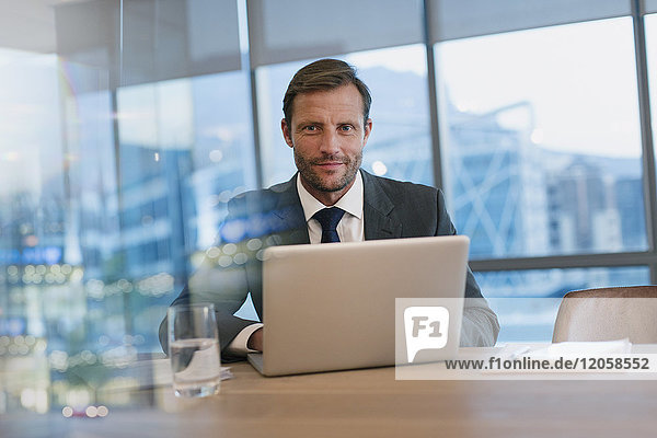 Portrait serious businessman working at laptop in conference room