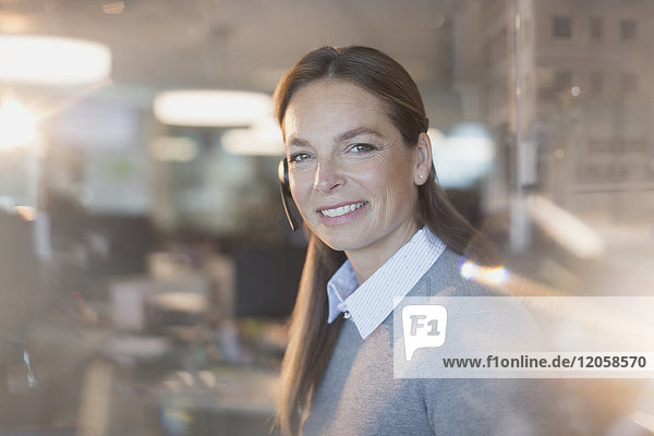 Porträt einer lächelnden  selbstbewussten Geschäftsfrau mit Headset im Büro