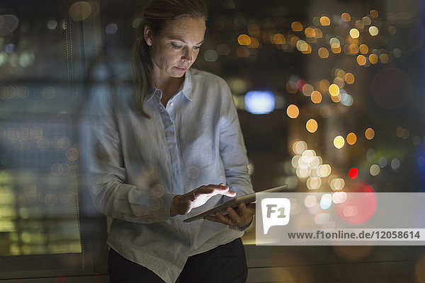 Geschäftsfrau arbeitet nachts im Büro an einem digitalen Tablet