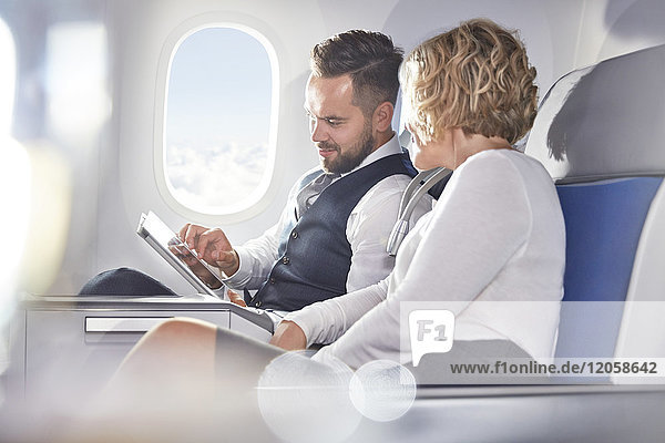 Geschäftsmann und Geschäftsfrau mit digitalem Tablett im Flugzeug