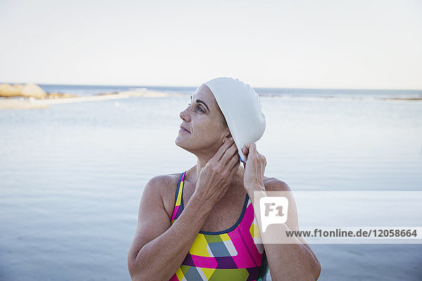 Weibliche Schwimmerin  die ihre Haare in die Badekappe der Meeresbrandung steckt