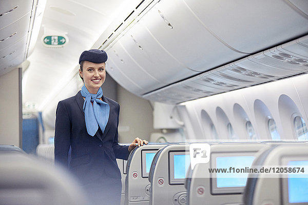 Portrait lächelnde  selbstbewusste Flugbegleiterin im Flugzeug