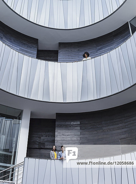 Portrait Geschäftsleute stehen auf architektonischen  modernen Büro-Atrium-Balkonen