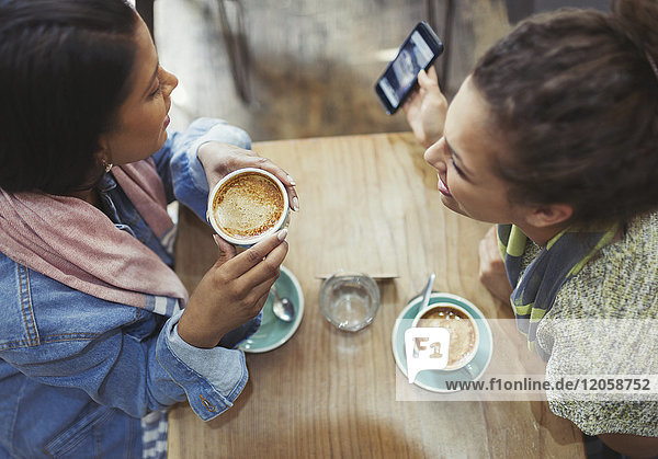 Freundinnen trinken Kaffee und telefonieren im Café