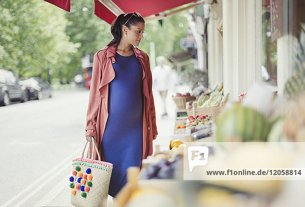 Schwangere Frau beim Einkaufen von Produkten im Schaufenster des Marktes