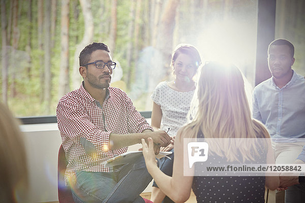 Attentive man listening to woman in group therapy session