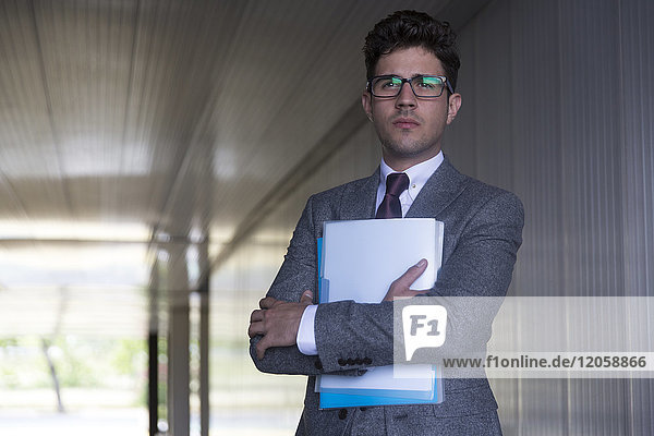 Porträt seriöser Geschäftsmann mit Papierkram im Büroflur