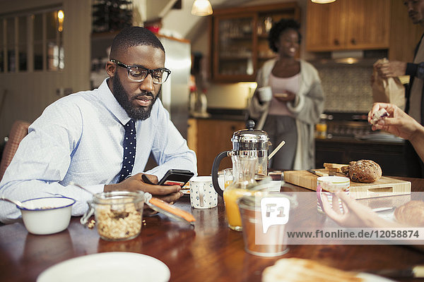 Geschäftsmann SMS mit Smartphone am Frühstückstisch