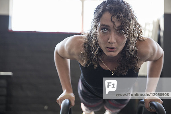 Porträt entschlossene junge Frau beim Liegestütz mit Ausrüstung im Fitnessstudio