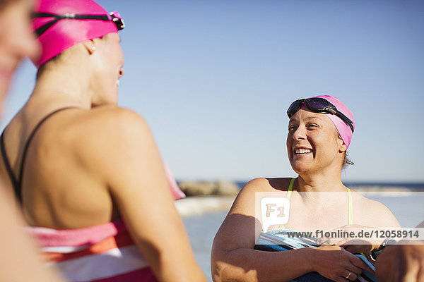 Smiling female open water swimmers drying off with towels