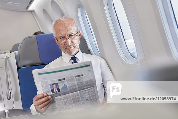 Geschäftsmann liest Zeitung im Flugzeug