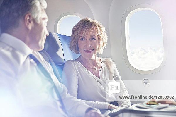 Geschäftsmann und Geschäftsfrau im Gespräch in der ersten Klasse im Flugzeug