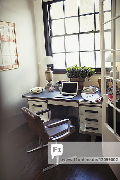 Laptop und Papierkram auf dem Schreibtisch im Home-Office