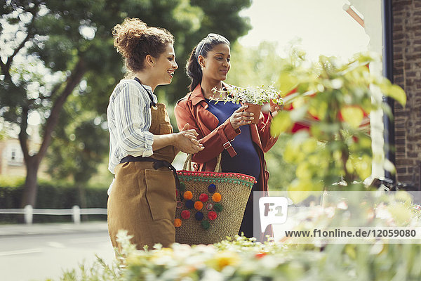 Floristin hilft schwangeren Einkäufern mit Topfpflanzen im Blumengeschäft