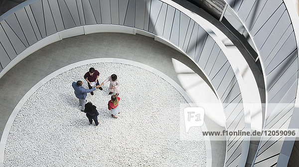 Blick von oben Geschäftsleute beim Händeschütteln im runden  modernen Büro-Atrium-Hof