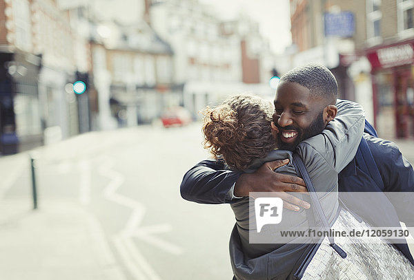 Fröhliches  liebevolles junges Paar  das sich auf einer sonnigen Stadtstraße umarmt.