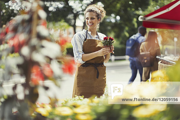 Smiling female florist working at flower shop storefront