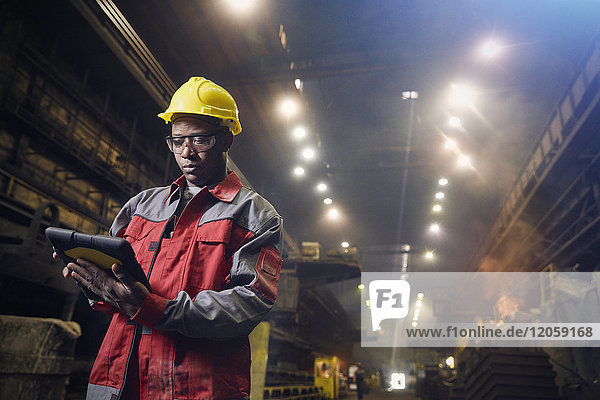 Steelworker using digital tablet in steel mill
