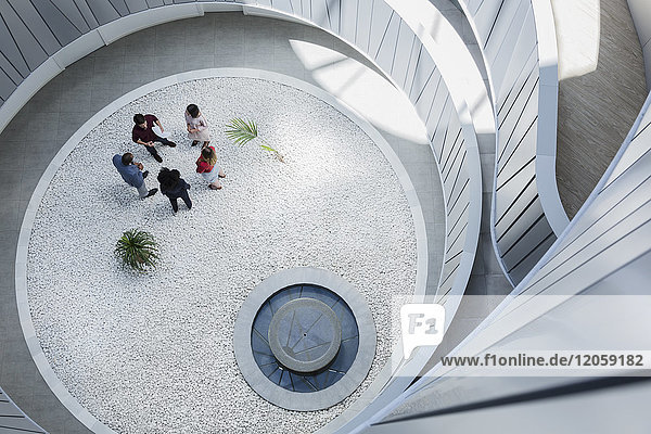View from above business people talking in round modern office atrium courtyard