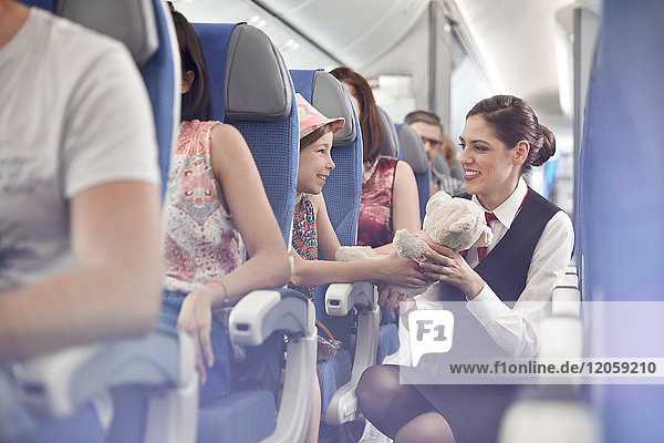 Mädchen zeigt Teddybär an Flugbegleiterin im Flugzeug