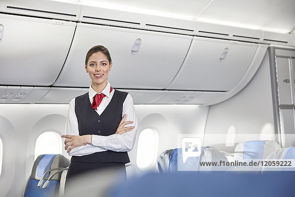 Portrait lächelnde  selbstbewusste Flugbegleiterin im Flugzeug