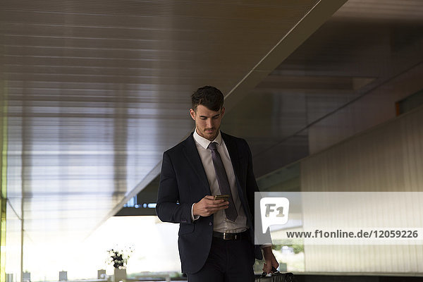 Businessman texting with smart phone in office lobby
