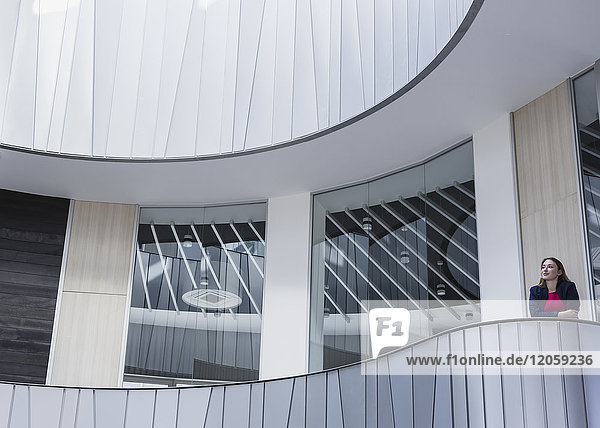 Nachdenkliche Geschäftsfrau auf dem architektonischen  modernen Bürobalkon