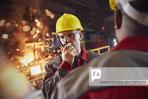 Steelworker talking  using walkie-talkie in steel mill