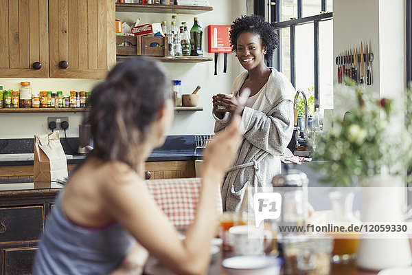 Smiling lesbian couple enjoying coffee and breakfast in kitchen