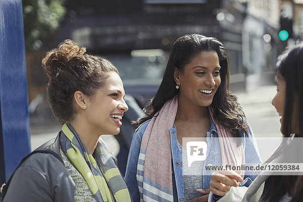 Smiling female friends talking on urban street