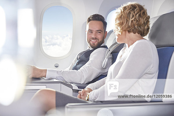 Lächelnder Geschäftsmann und Geschäftsfrau reden im Flugzeug