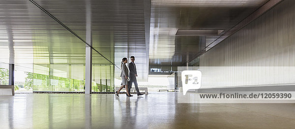 Geschäftsmann und Geschäftsfrau zu Fuß in der modernen Bürolobby
