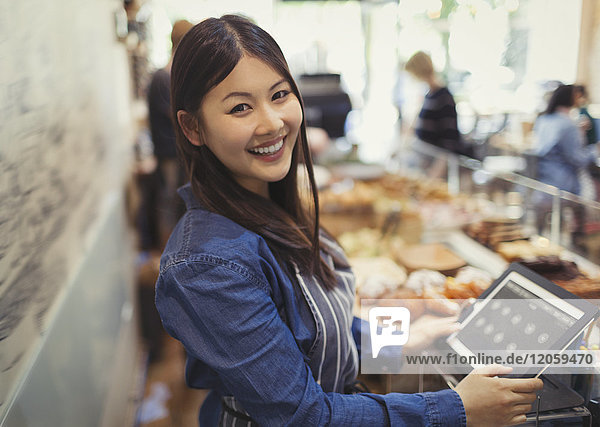 Portrait smiling  confident female cashier at cash register in cafe