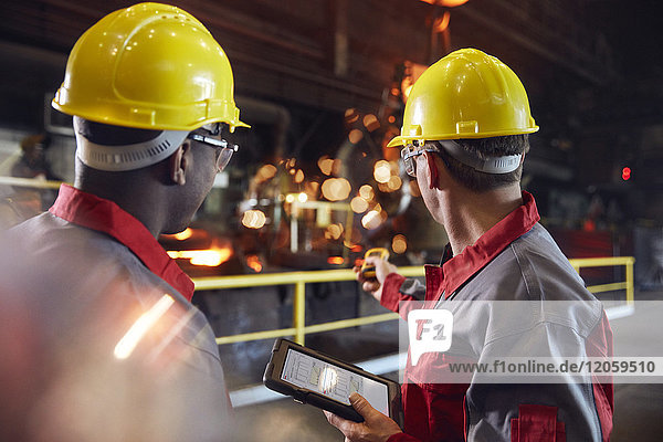 Supervisor and steel worker with digital tablet working in steel mill