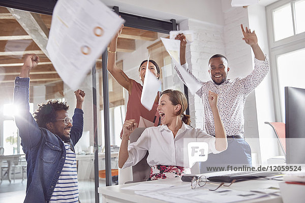 Überbordende Geschäftsleute feiern  werfen Papierkram ins Büro