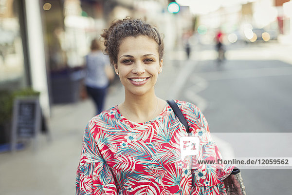Portrait smiling young woman on urban street
