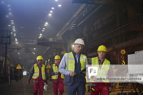 Supervisor und Stahlarbeiter beim Gehen und Sprechen im Stahlwerk