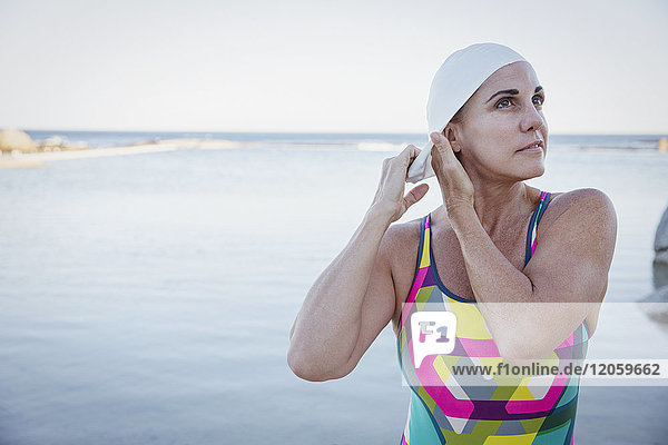 Female open water swimmer adjusting swimming cap at ocean