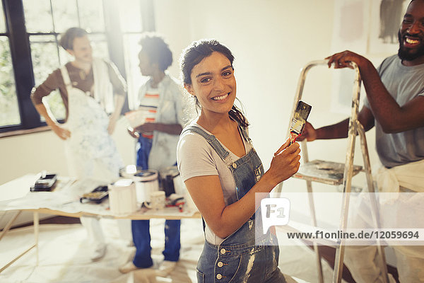 Portrait lächelnde  selbstbewusste Frau beim Malen im Wohnzimmer mit Freunden