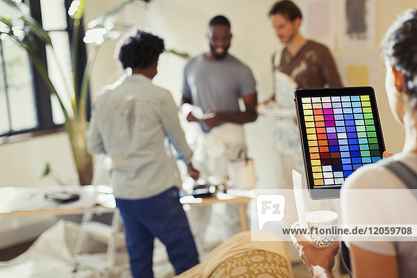 Junge Frau mit digitalem Tablett zum Betrachten digitaler Farben  Malen im Wohnzimmer