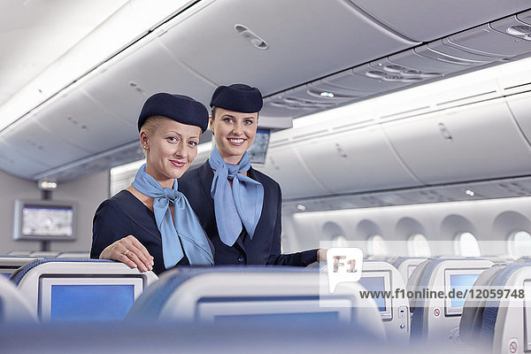 Portrait lächelnde  selbstbewusste Flugbegleiterinnen im Flugzeug