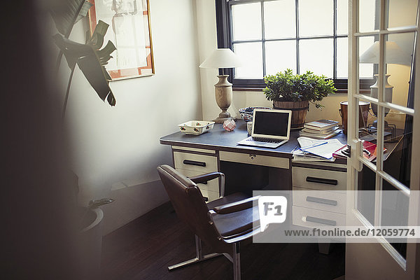 Laptop und Papierkram auf dem Schreibtisch im Home-Office