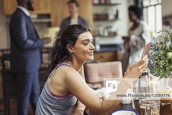 Young woman texting with smart phone at breakfast table