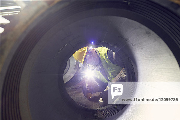 Stahlarbeiter mit Taschenlampe zur Untersuchung von Stahlteilen im Stahlwerk