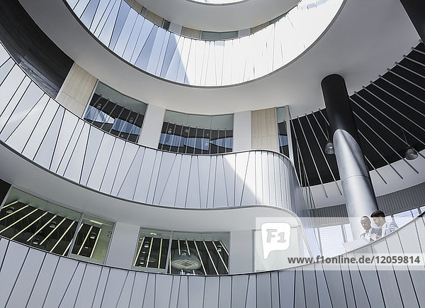 Geschäftsleute diskutieren Papierkram auf architektonischem  modernem Büro-Atrium-Balkon