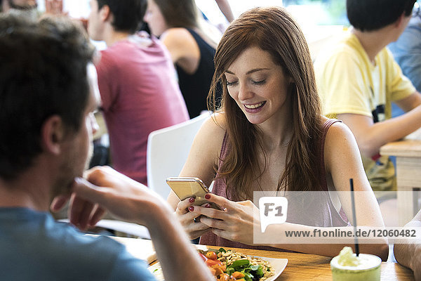 Frau mit Smartphone im Restaurant