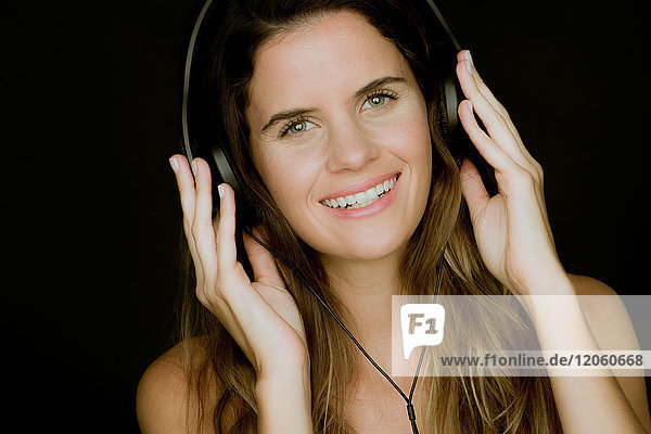 Young woman listening to headphones and smiling cheerfully  portrait