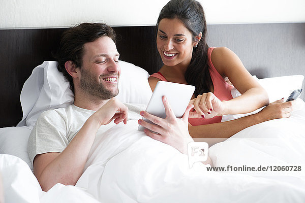 Paar mit digitalem Tablett im Bett