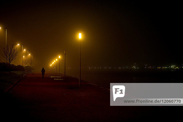 Person walking along deserted waterfront at night